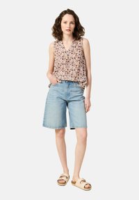 Blusa sin mangas floral de tejido ligero, combinada con pantalones cortos de mezclilla azul claro y sandalias de tira en color tostado con suela de corcho trenzado.