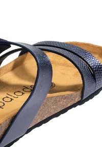 Sandalo blu navy con strisce incrociate, realizzato in pelle testurizzata, con soletta in sughero e una morbida imbottitura in suede. Marchio discreto visibile.