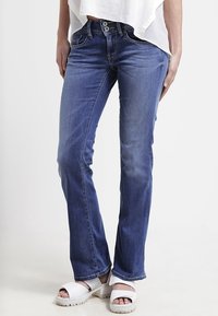 Blå denimjeans med rak passform, med tryckknapp och två framfickor. Bärs med vita platåsandaler.