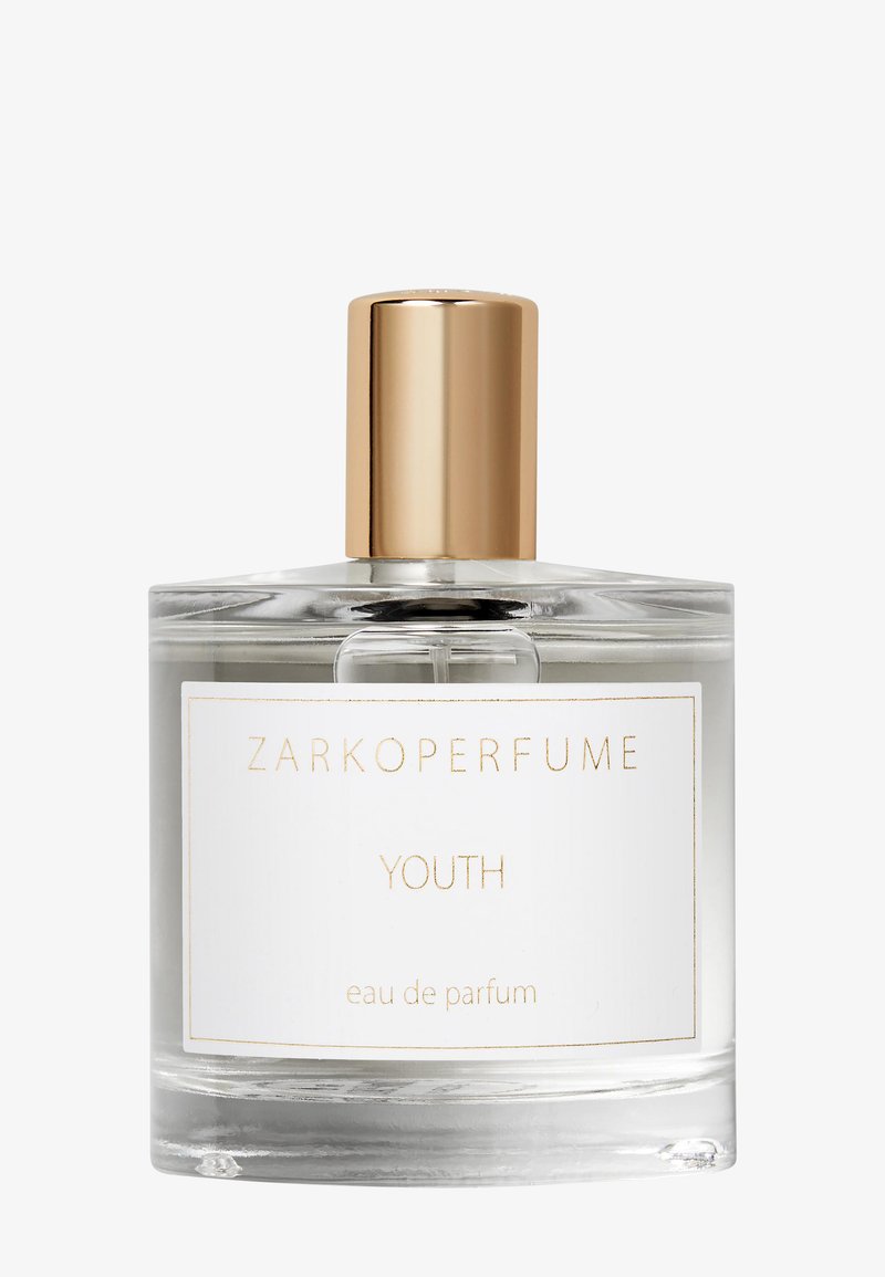 Botella de perfume de cristal transparente etiquetada como "Zarkoperfume Youth eau de parfum" con una tapa cilíndrica dorada brillante sobre un fondo blanco.