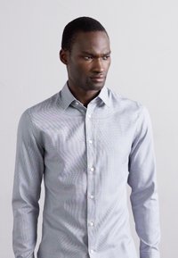 Light blue button-up shirt with a subtle check pattern, long sleeves, and a classic collar. Fabric appears smooth with a slight sheen.