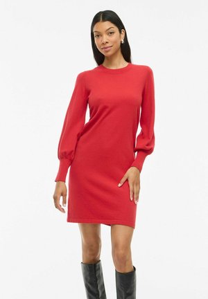 Robe tricotée rouge avec de longues manches bouffantes et des poignets côtelés, dotée d'un col rond classique. Texture lisse et silhouette ajustée.