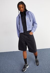 Lys blå cropped hettegenser med snøring, svart genser med høy hals, svarte denimshorts og svarte sneakers med hvite detaljer.