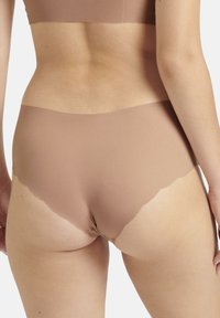 Jasnobrązowa bielizna bezszwowa z falbaniastym wykończeniem. Wykonana z gładkiego materiału, zaprojektowana z myślą o eleganckim i wygodnym dopasowaniu.