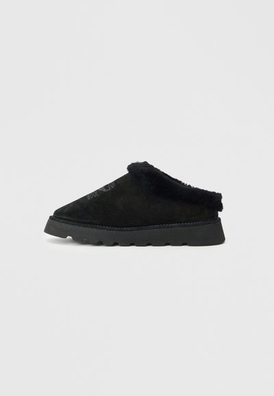 Μαύρο παπούτσι slip-on από σουέτ με φουντωτό μαύρο περίγραμμα. Διαθέτει παχιά, υφή σόλα με αυλακώσεις για πρόσφυση και σχέδιο αιχμηρής μύτης.