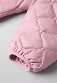 Helle rosa gesteppte Jacke mit einem Ärmel und elastischem Bündchen, das eine glatte Textur und ein durchgehendes Rautenmuster aufweist.