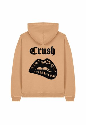 Sweatshirt à capuche en coton beige avec un design graphique noir de lèvres et le mot "Crush" imprimé au-dessus. Poignets et ourlet côtelés.