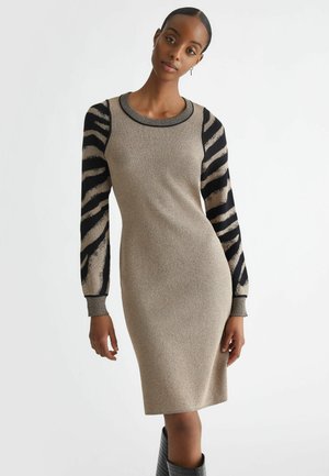 Abito a maglia con silhouette aderente, corpo oro e beige, maniche a strisce nere, scollo rotondo e polsini a costine.