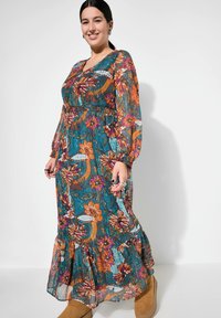 Blumenkleid im Maxistil in Teal mit orangefarbenen und lila Mustern. Mit langen Ärmeln, einem gerafften Bund und einem gestuften Saum. Geeignet für verschiedene Anlässe.