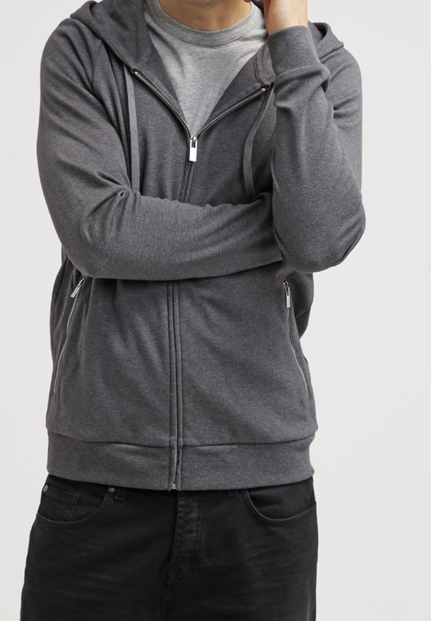 Sweat à capuche gris à fermeture éclair en tissu doux avec manches longues, poches avant et capuche à cordon, superposé à un t-shirt gris clair.