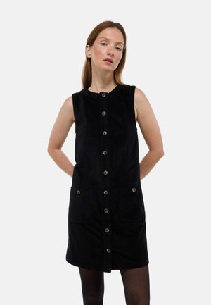 Robe en velours côtelé noir avec un col rond, fermeture à boutons sur le devant et deux poches avant. Texture lisse avec une silhouette ajustée.