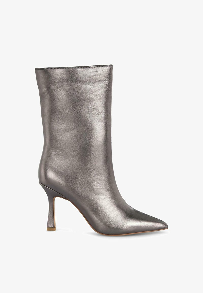 Bottine argentée métallique avec un bout pointu, finition en cuir lisse et un talon haut élancé. Design épuré avec peu de couture visible.