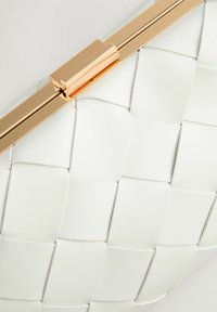 Biała pleciona kopertówka ze skóry z błyszczącym złotym metalowym zapięciem i ramą.