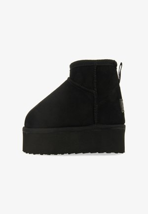 Bottine en suède noir avec une semelle plateforme épaisse, dotée d'un bout arrondi et de coutures le long des seams.