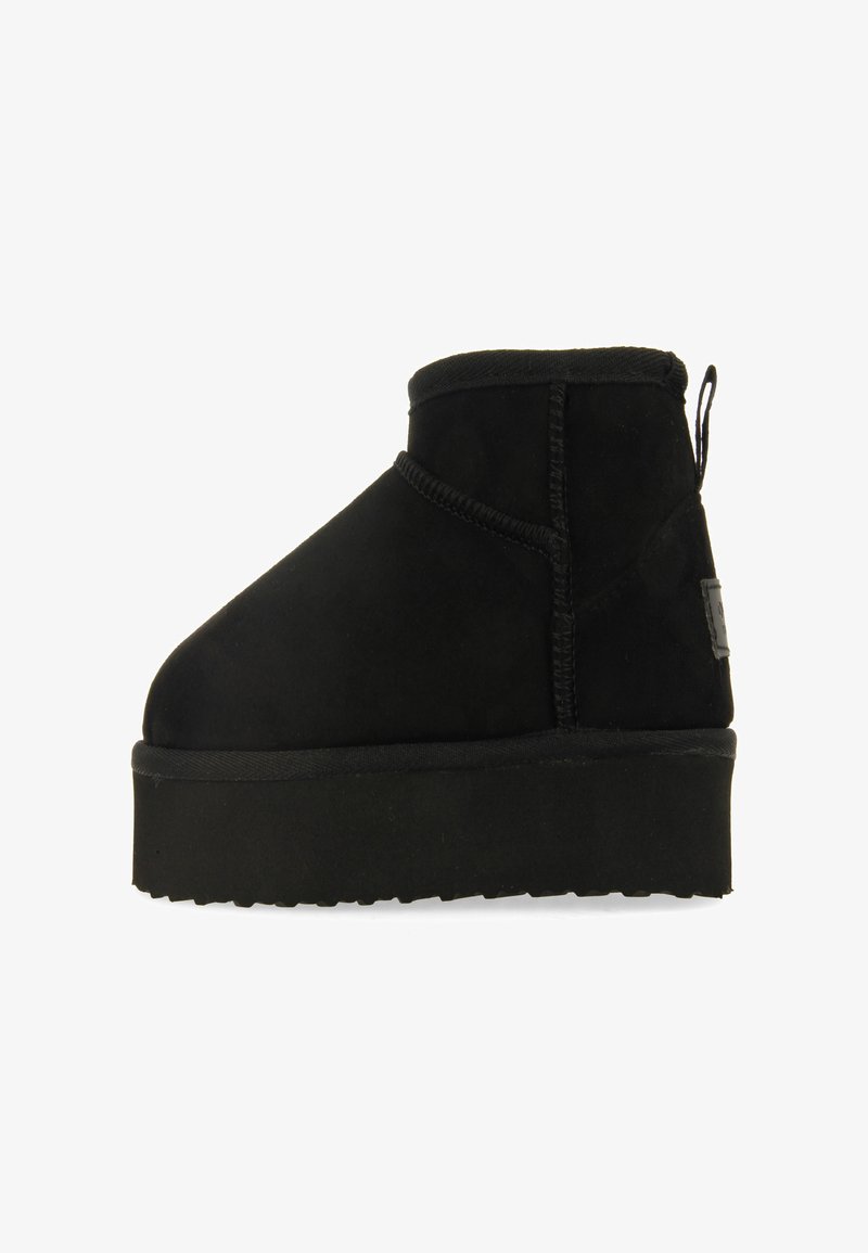 Botín de ante negro con suela gruesa de plataforma, que presenta una punta redondeada y detalles de costura a lo largo de las costuras.