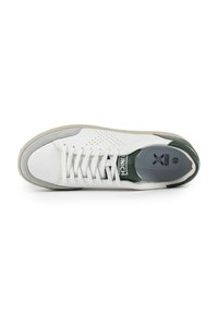 Sneaker bianca con accenti verdi, dotata di una tomaia in pelle liscia, una suola intermedia testurizzata e lacci piatti. Dettagli perforati nella zona della punta.