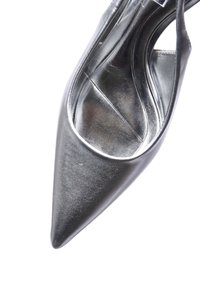 Scarpa nera in pelle con tacco alto e punta affusolata, texture liscia e dettagli metallici all'interno. Sides aperti per un design con lacci.