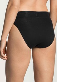 Culottes noirs en coton avec un design taille haute, texture lisse et taille élastique. Présentent une couture minimale et un dos sans coutures.