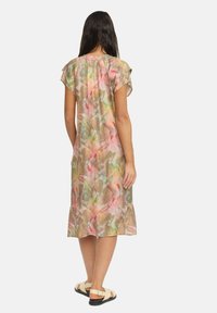 Maxiklänning i blommönster med pastellfärger i rosa, grönt och beige. Tillverkad av lätt tyg, med korta ärmar och en avslappnad passform.