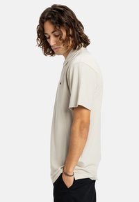 Lys beige polo shirt lavet af blødt stof. Har korte ærmer, en klassisk krave og et lille logo på brystet.