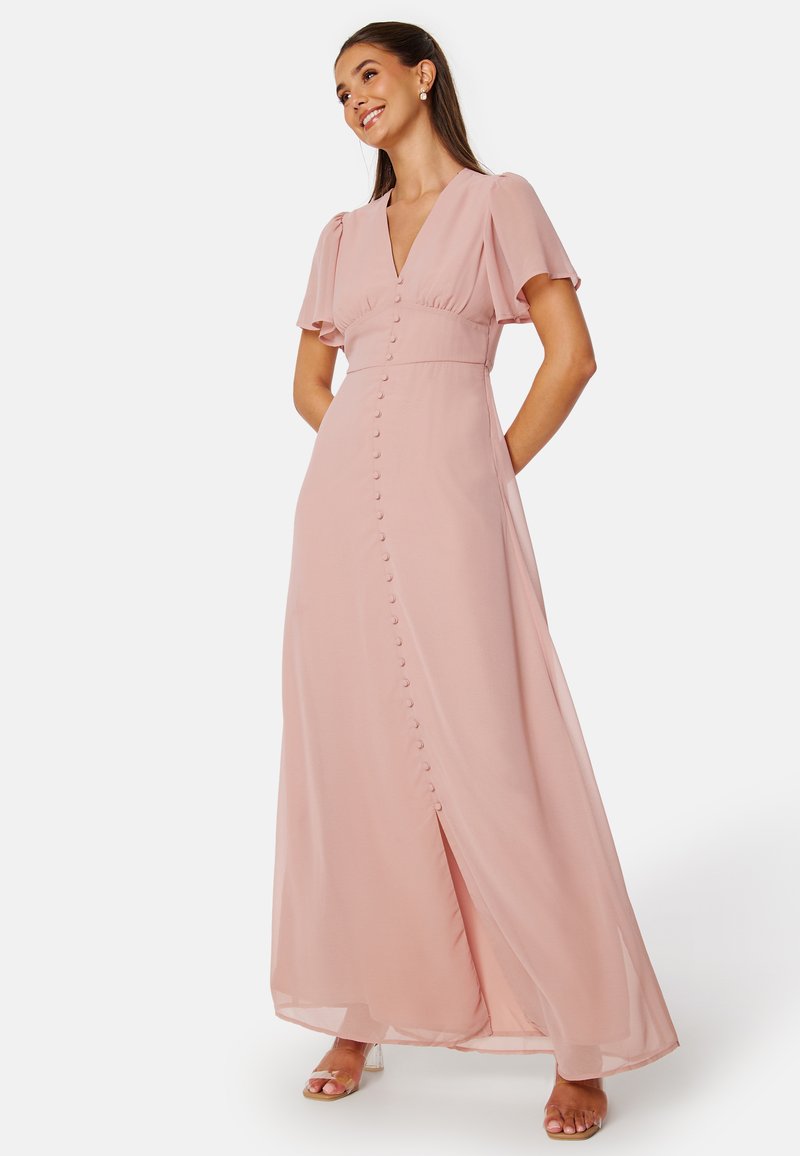 Robe maxi en tissu rose doux avec des manches courtes évasées, décolleté en V profond et fermeture à bouton sur le devant s'étendant jusqu'à une fente sur le côté.