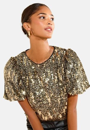 Gold sequined top with short puff sleeves, featuring a round neckline and textured fabric. Accentuated by a contrasting black trim.