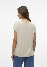 Top beige a maniche corte con una vestibilità rilassata, scollatura rotonda e texture a coste, abbinato a jeans in denim blu.