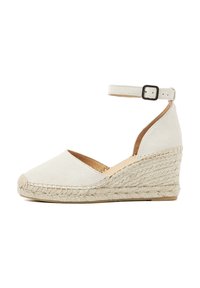 White suede wedge sandal with an ankle strap, braided jute sole, rounded toe, and a textured finish.