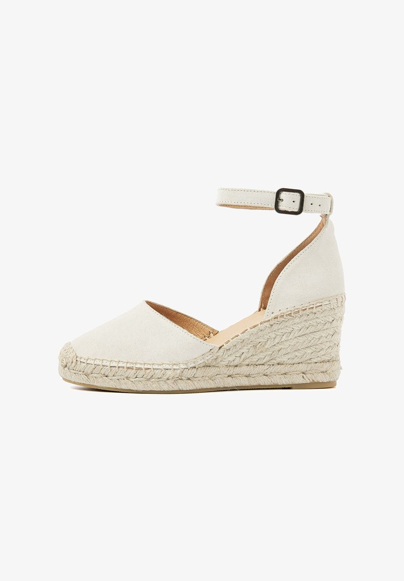 White suede wedge sandal with an ankle strap, braided jute sole, rounded toe, and a textured finish.