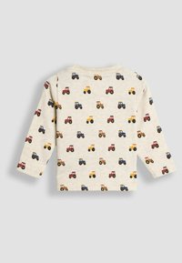 Cremfarbener Langarm-T-Shirt für Kleinkinder mit roten, blauen und gelben Traktor-Mustern überall, von hinten gezeigt.