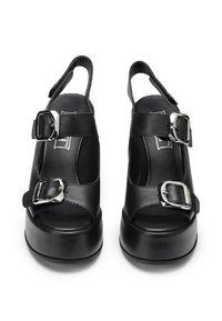 Sandali platform neri con punta aperta, design slingback, ampiezza delle cinghie con fibbie in argento e texture in pelle liscia.