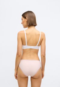 Soutien-gorge blanc avec bretelles ajustables et fermeture à agrafes, assorti à un slip rose pâle orné d'une délicate bordure en dentelle. Tissu lisse et extensible.