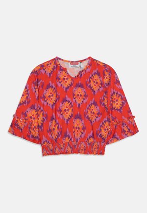 Blusa roja recortada con estampado floral en naranja y morado, mangas cortas con volantes y cintura elástica fruncida.