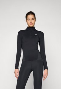 Črn športni dolgi rokav s solidnim ovratnikom z zadrgo, raztegnjenim materialom, prileganjem in mrežnimi stranskimi ploščami za prezračevanje. Prikazana je znamka Under Armour.