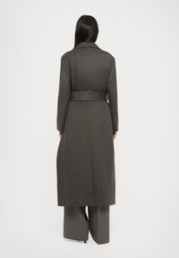 Long, gray wool coat with a belted waist, notch collar, and straight-cut silhouette. Textured fabric with a tailored design.