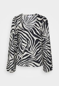 Blouse imprimé zèbre avec manches longues, encolure en V, et tissu doux avec un motif noir et blanc. Rayures ondulées distinctives sur l'ensemble.