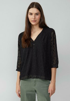 Chemisier noir avec un décolleté en V, des manches 3/4 et un motif léopard texturé. Fabriqué en tissu léger et transparent avec une coupe légèrement ample.