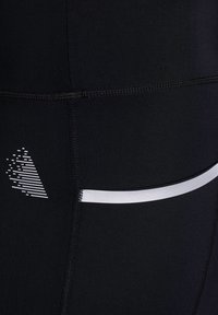 Crne sportske tajice glatke teksture, s reflektirajućom srebrnom prugom i grafičkim dizajnom malih vertikalnih linija.