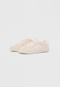 Le sneaker rosa chiaro presentano una tomaia in maglia testurizzata, dettagli bianchi, lacci rotondi e una suola imbottita con un motivo geometrico.