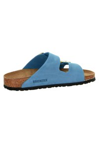 Blue suede Birkenstock sandal with cork footbed and black rubber sole. Features two cut-out straps and a backless design for easy slip-on.