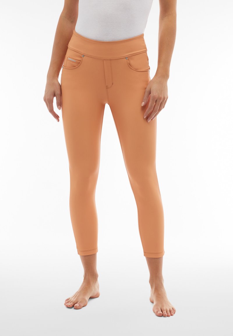 Leggings color pesca con vita alta, realizzati in tessuto elasticizzato, con tasche frontali e dettagli di cucitura. Lunghezza cropped.
