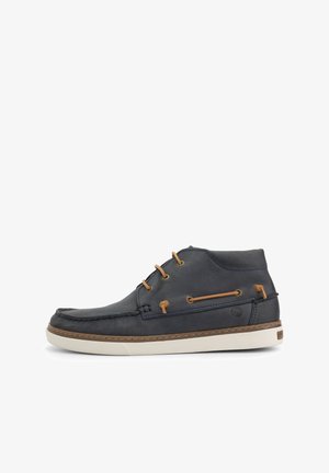 Donkerblauwe leren hoge schoen met beige accenten, een gestikte neus en een bruine rubberen zool. Beschikt over een vetersluiting en decoratieve zijnaad.