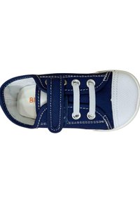 Zapato de lona azul marino con puntera de goma blanca, con dos ojales plateados, cordones blancos y una correa de velcro en la parte superior.