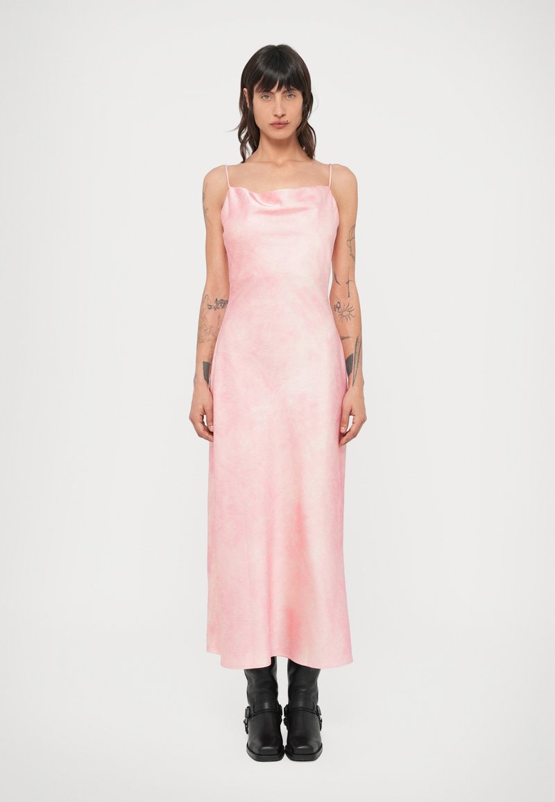 Ružové maxi šaty bez rukávov s hladkým, lesklým povrchom a jemným mramorovým vzorom. Štýlovo doplnené čiernymi koženými členkovými čižmami.