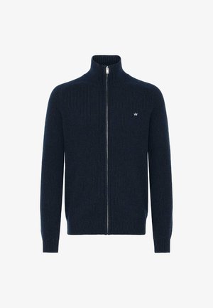 Mørkeblå ribbestrikket cardigan med høy krage, glidelås foran og liten logo på venstre bryst. Strukturert strikket stoff.