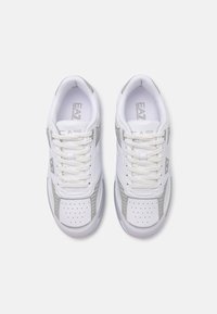 Fehér sneaker, szürke részletekkel, sima bőrből készült felsőrésszel, perforált részletekkel, párnázott nyelvvel és textúrázott fűzőkkel.
