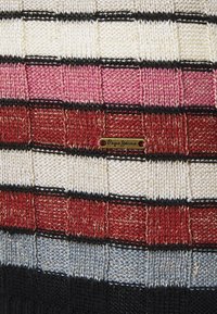 Le tissu tricoté multicolore présente des motifs en grille alternés en blanc, rose, rouge et noir avec une étiquette dorée "Pepe Jeans".