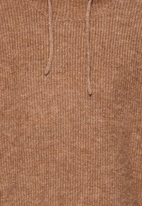 Bruine gebreide trui met een gestructureerd patroon. Heeft een hoge halslijn en trekkoorden, wat zorgt voor een gezellige en casual uitstraling.