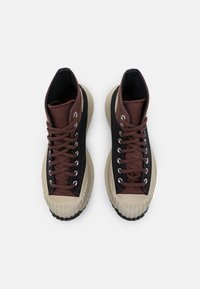 Vysoké tenisky s černým plátěným svrškem, hnědými textilními detaily, béžovými gumovými podrážkami a stříbrnými očky se šněrováním.