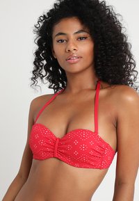 Crveni bikini gornji dio s naborima, halter trakama i bijelim točkicama. Glačan tekstura s čvrstim dizajnom koji pruža potporu.